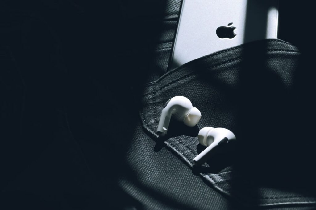 Wireless earbuds and a smartphone in a sunlit pocket, showcasing modern technology.