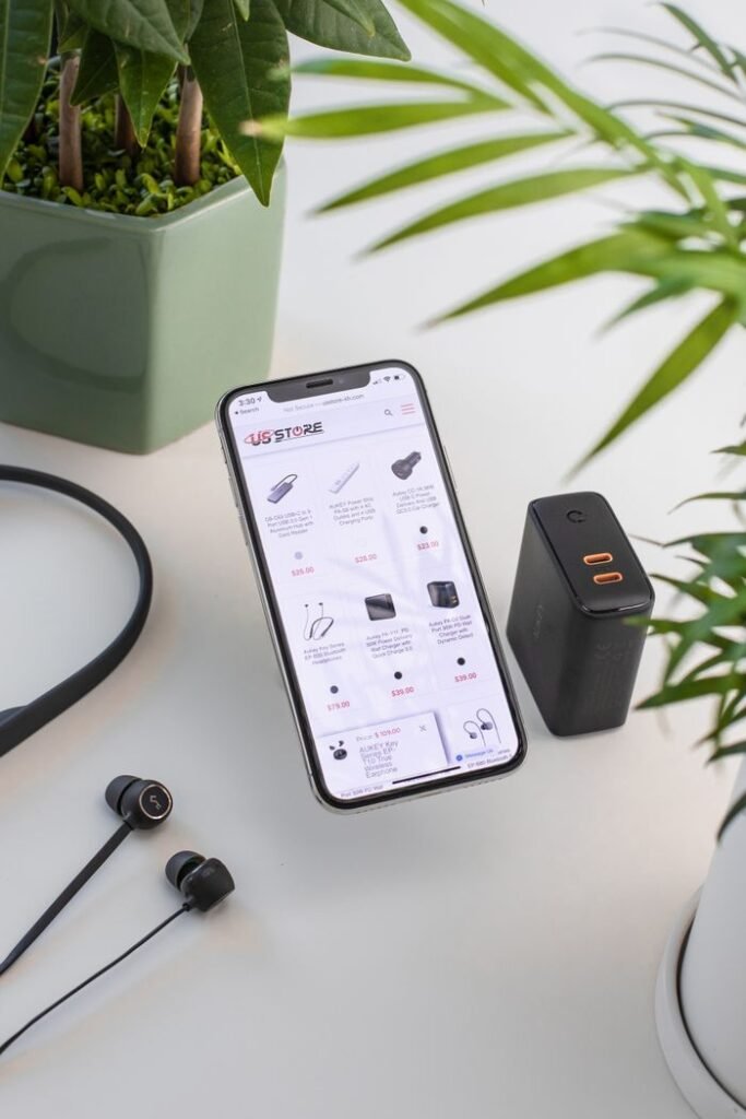 From above composition of modern mobile phone placed on working desk near uninterruptible power supply and wired earphones